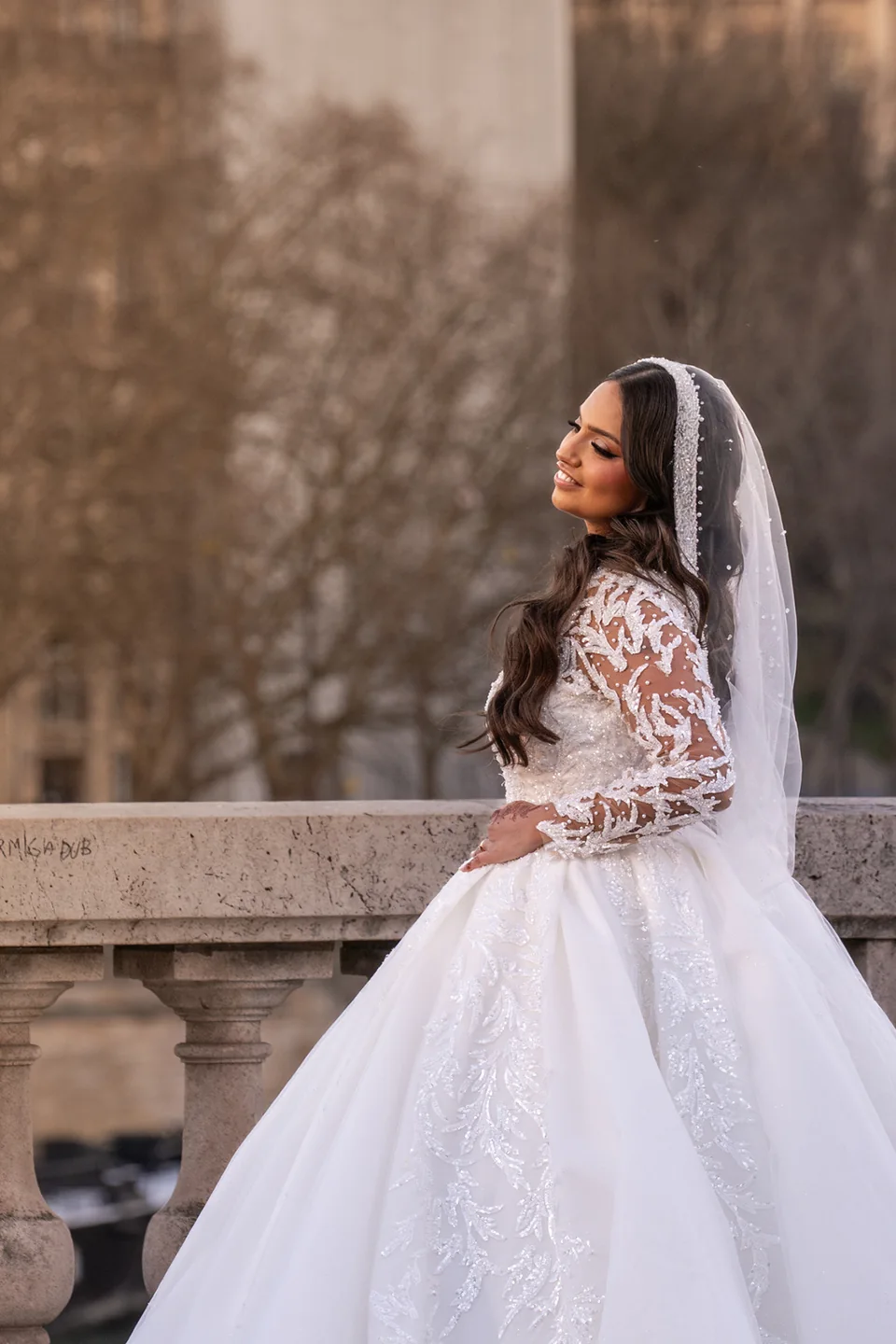 Une mariée en robe blanche, près d’une balustrade en pierre