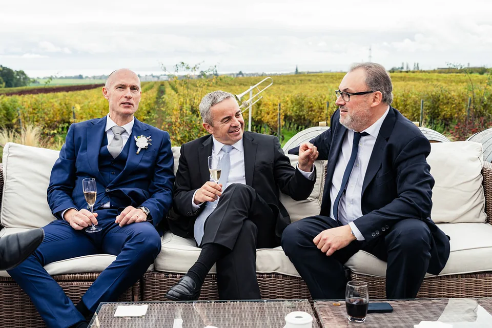Trois invités en costumes échangent avant la célébration