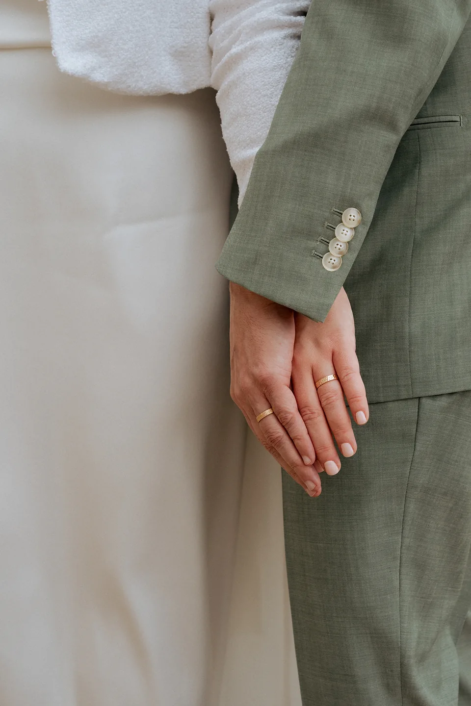 La main de la mariée et la veste du marié, un détail de leur union